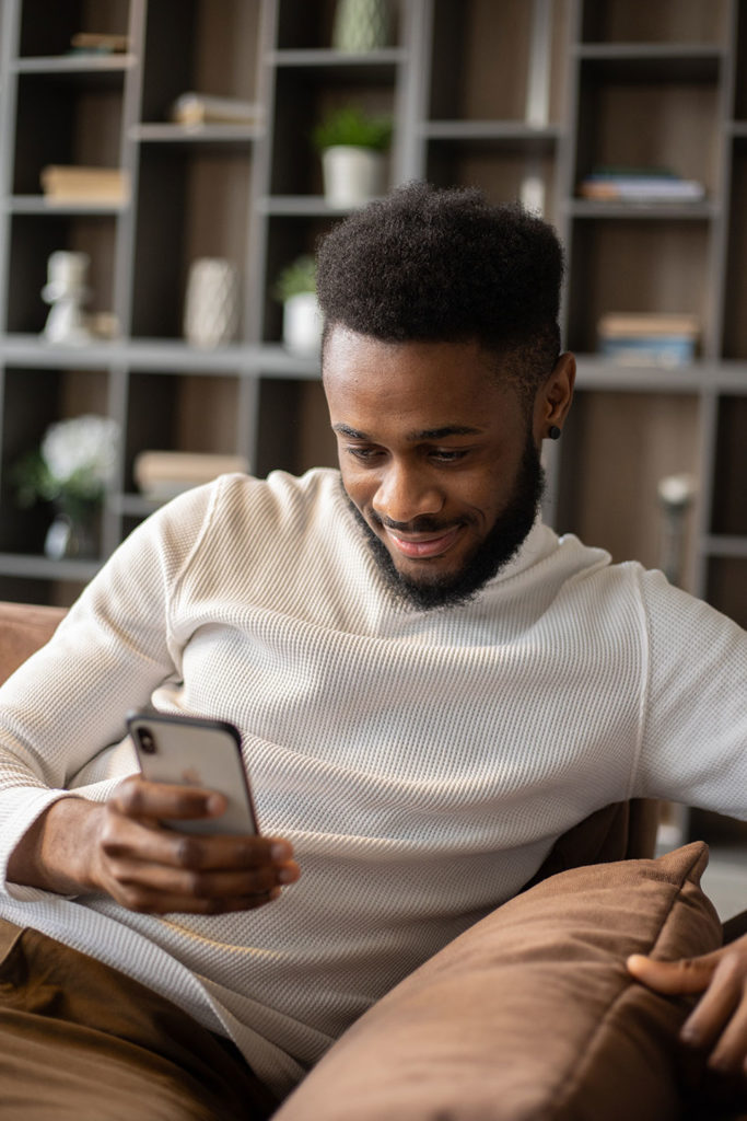 afro american man with snartphone at home on the couch